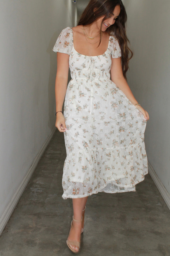 Woman wearing a white floral dress in a minimal indoor setting