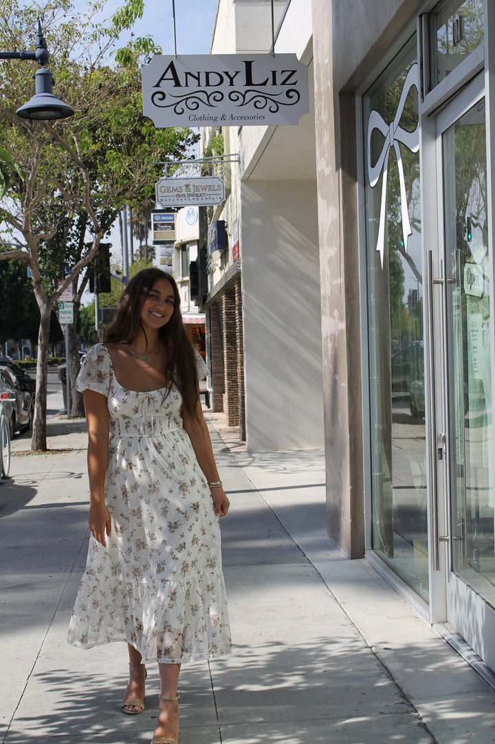 Woman in a floral dress walking past 'AndyLiz' clothing store.