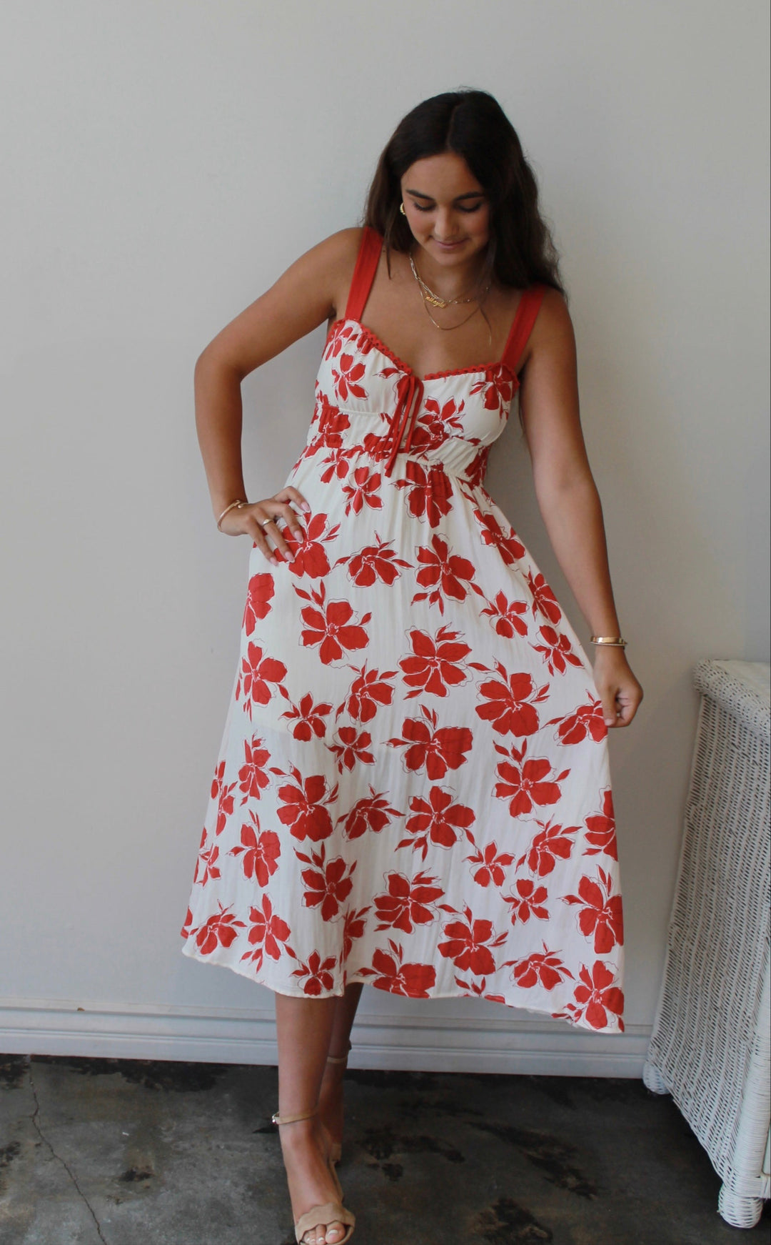 Woman wearing a white dress with red floral pattern indoors.