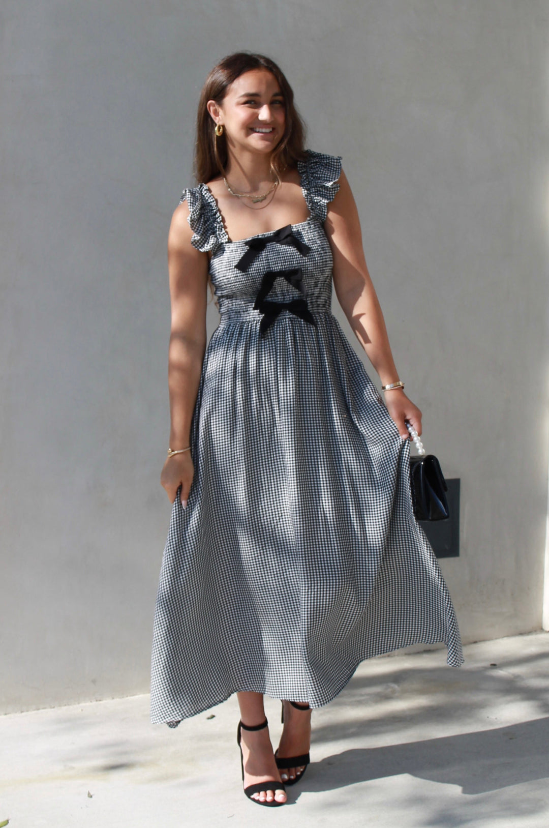Woman in a gray dress standing against a light-colored wall.