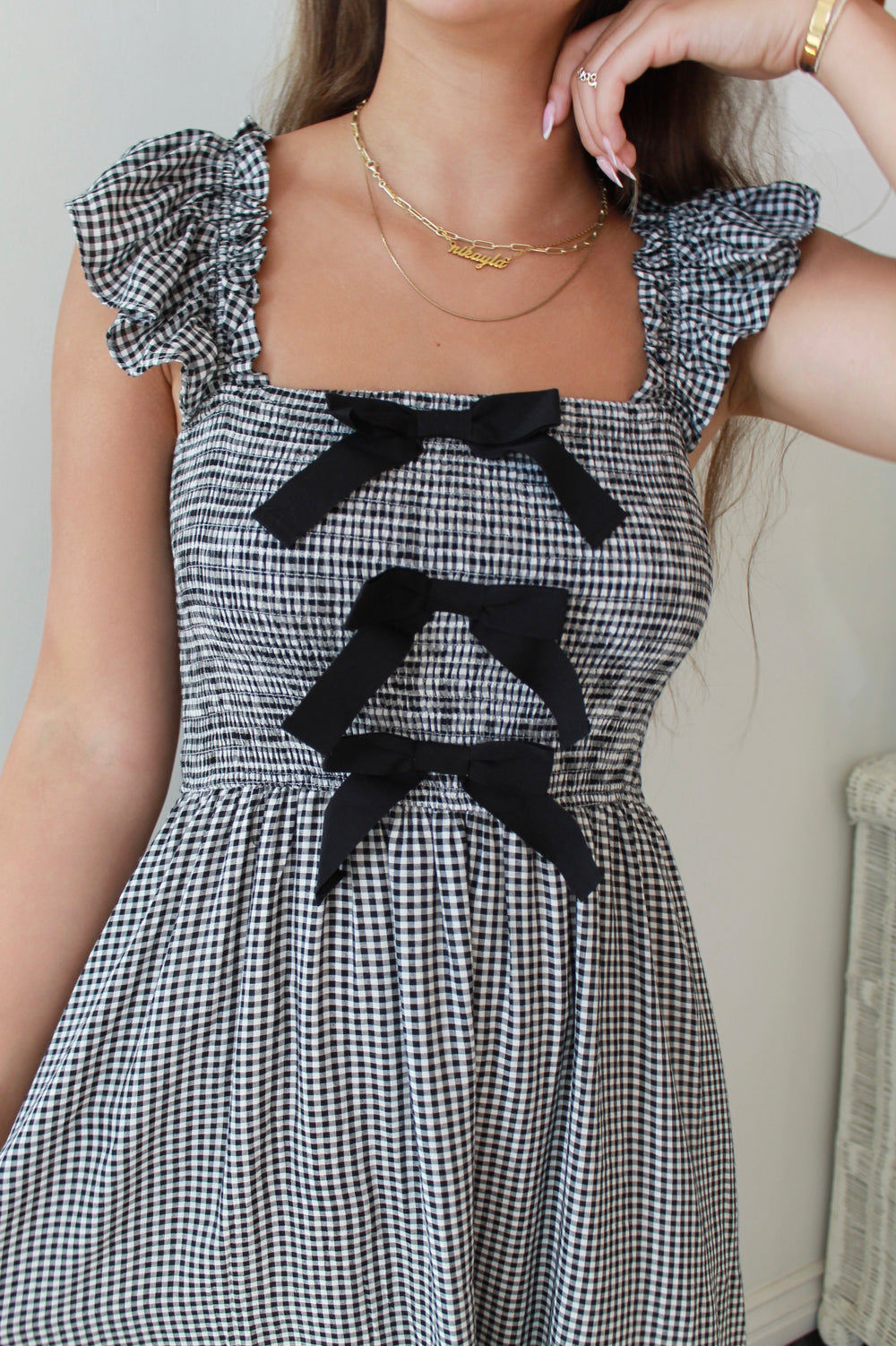 Black and white checkered dress with black bows worn by a person.