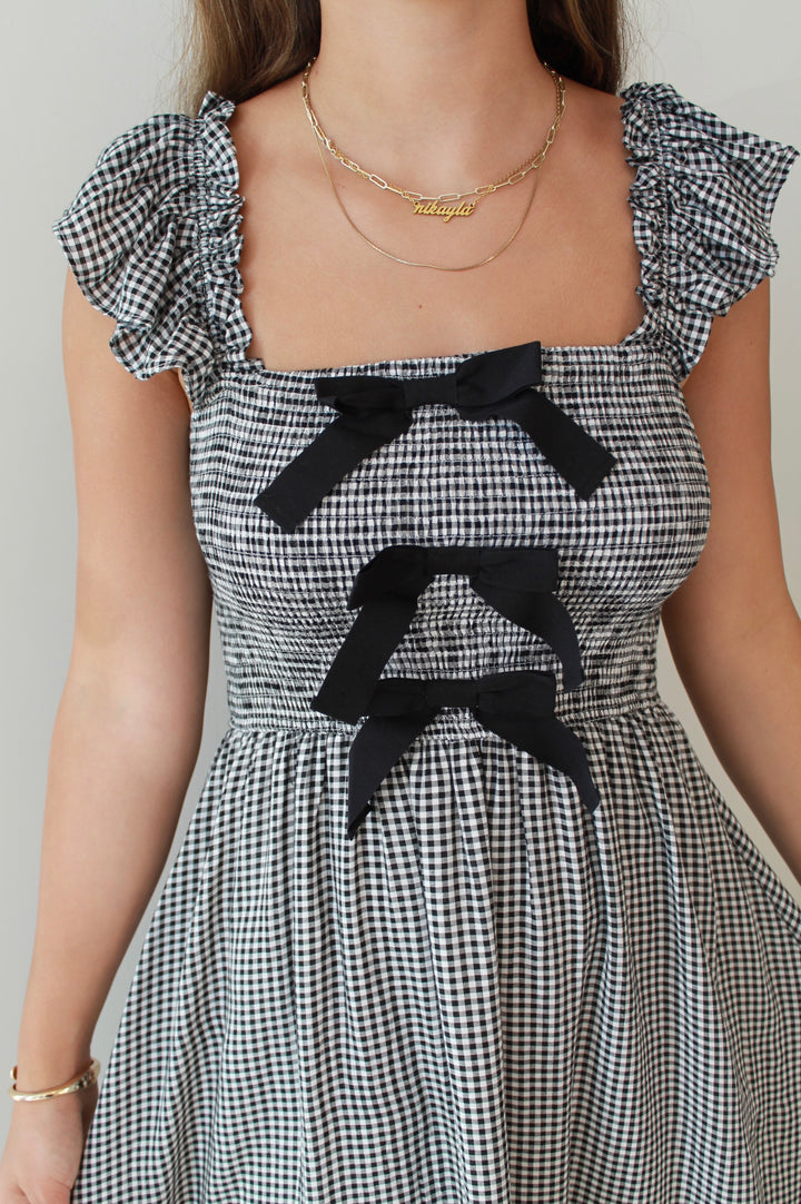 Black and white checkered dress with black bows on a plain background