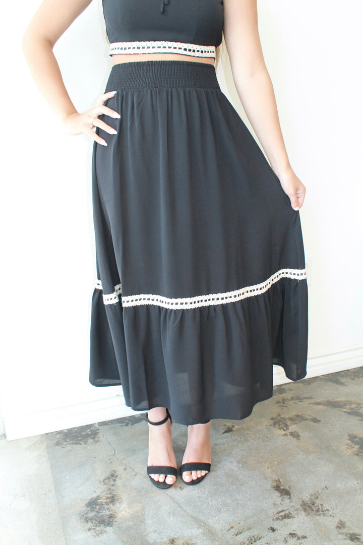 Person wearing a black skirt with white trim on a plain background