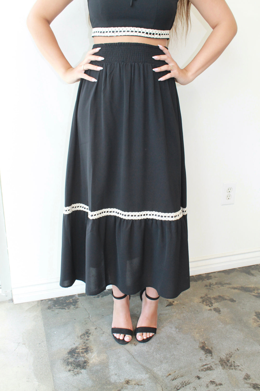 Person wearing a black skirt with white trim on a plain background