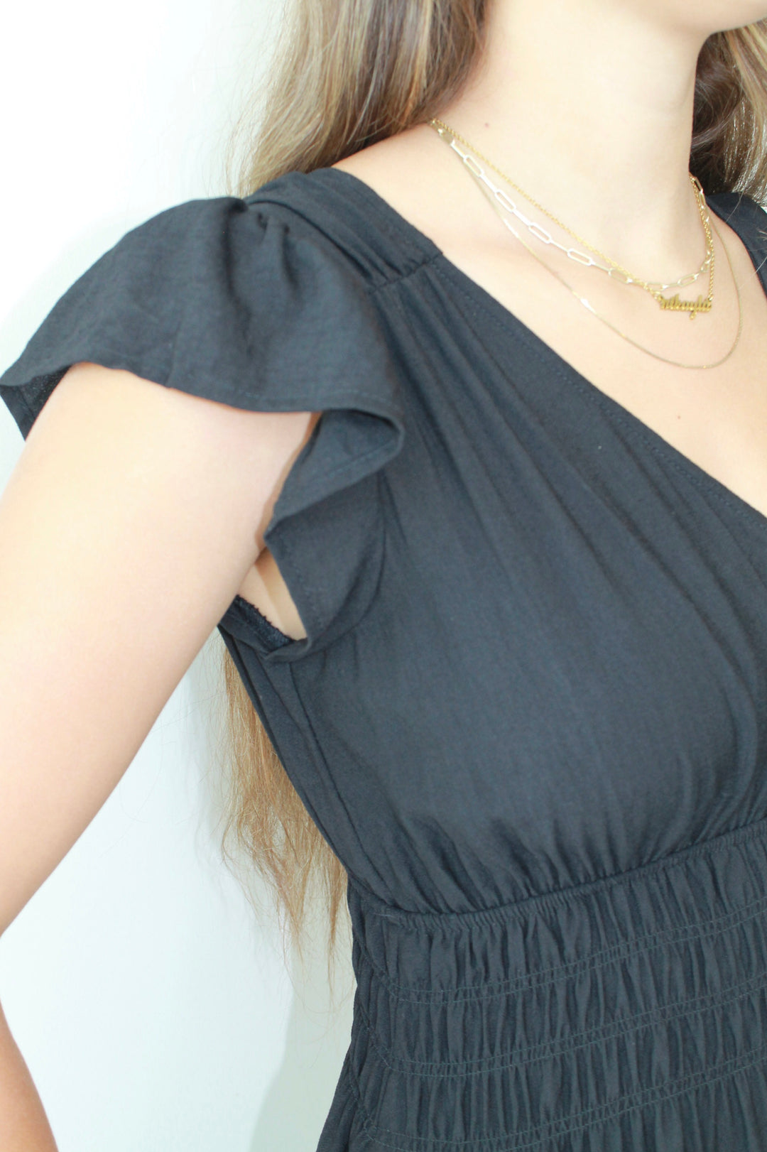 Gray dress with ruffled sleeves worn by a person on a white background