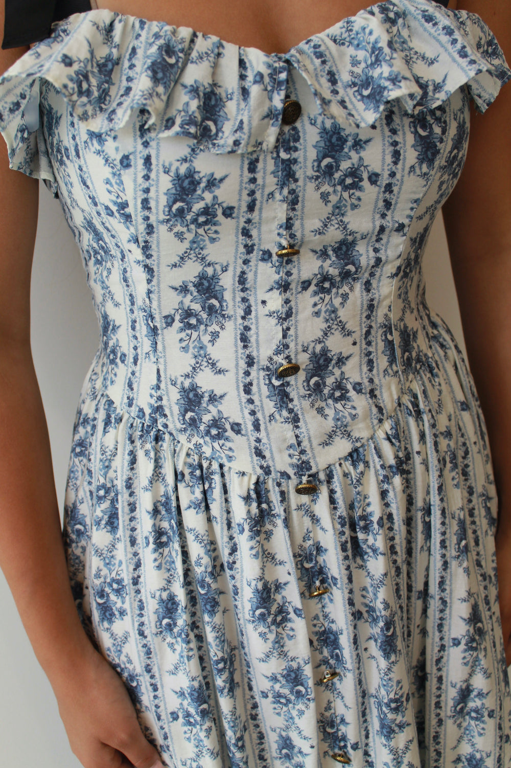 White dress with blue floral pattern and ruffled neckline.