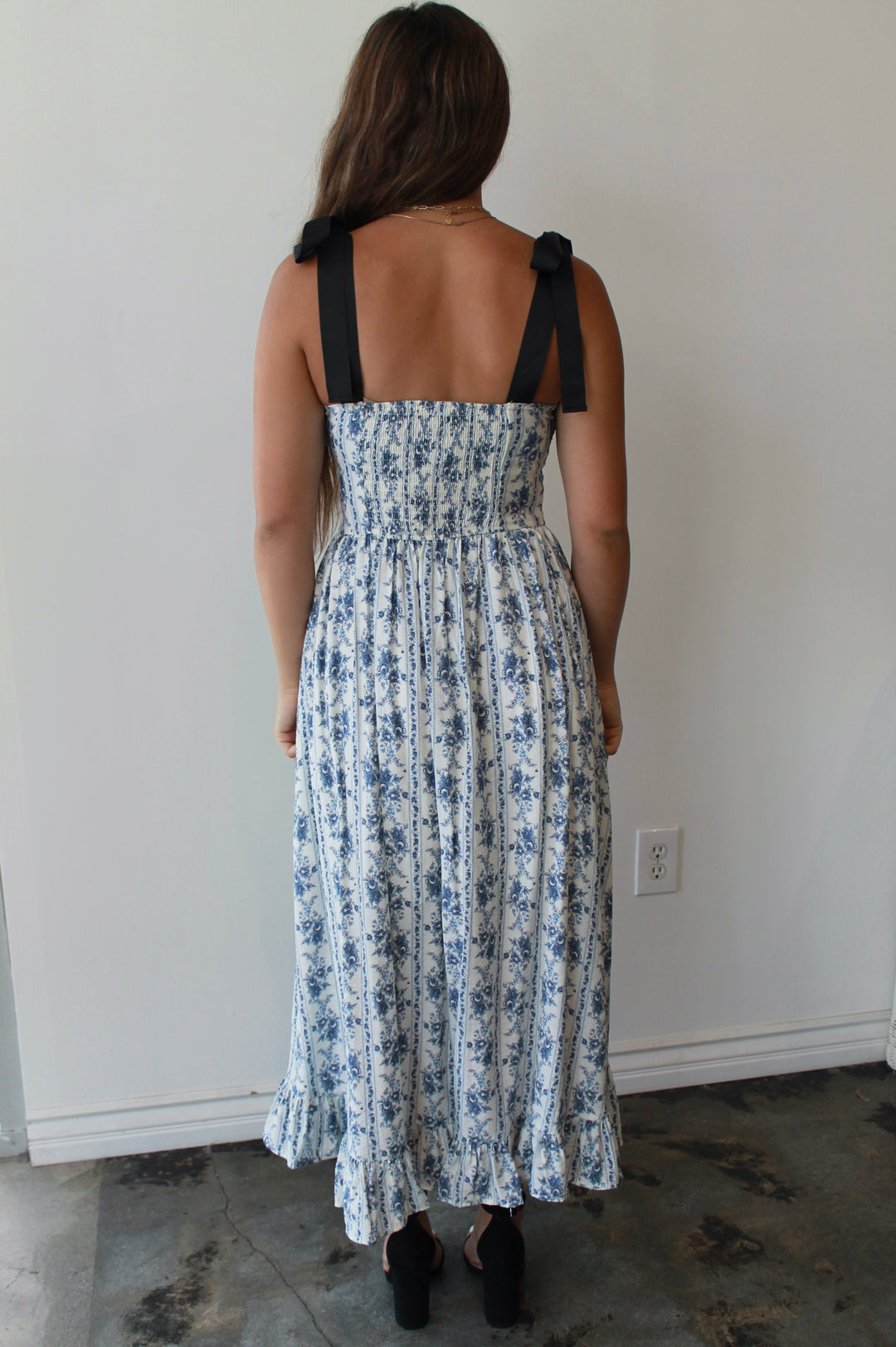 Woman wearing a floral dress with black straps in a minimal indoor setting
