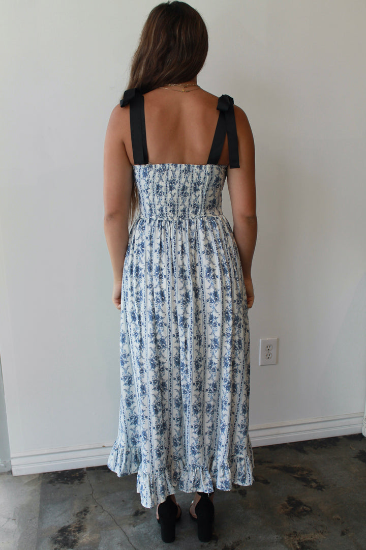 Woman wearing a floral dress with black straps in a minimal indoor setting