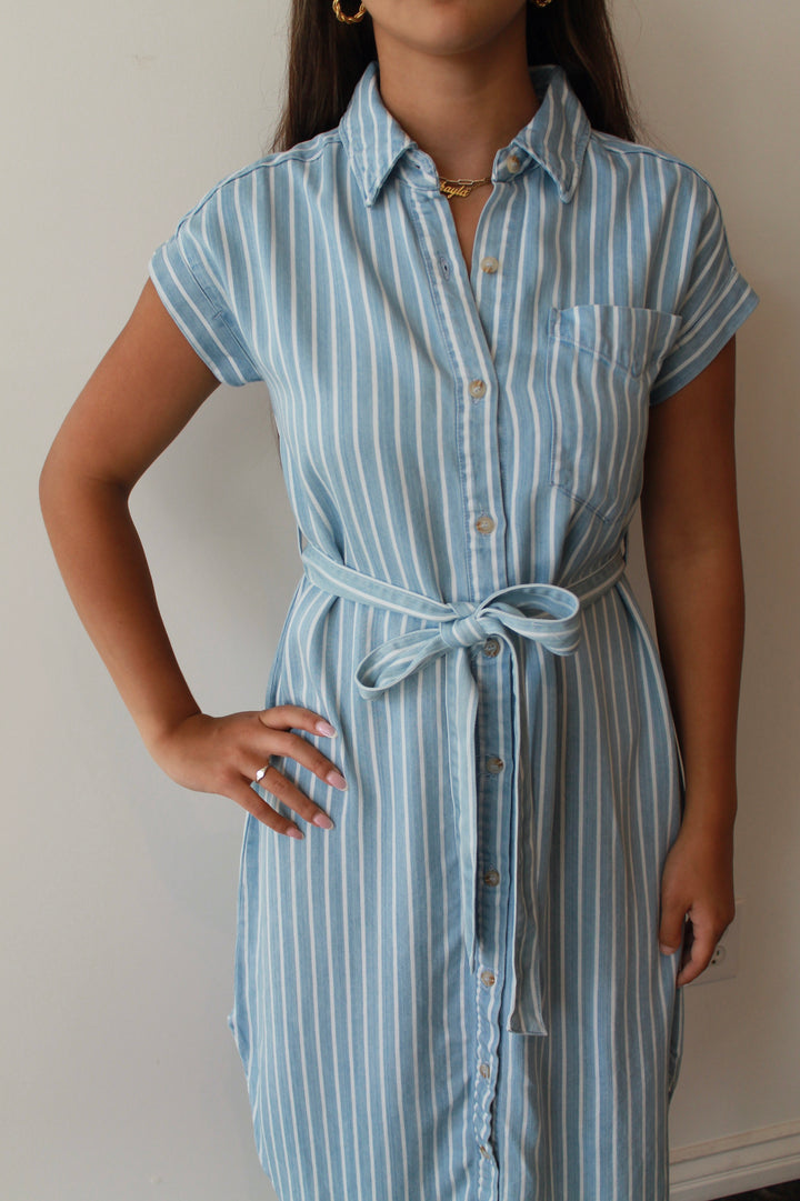 Woman wearing a blue and white striped dress against a plain background