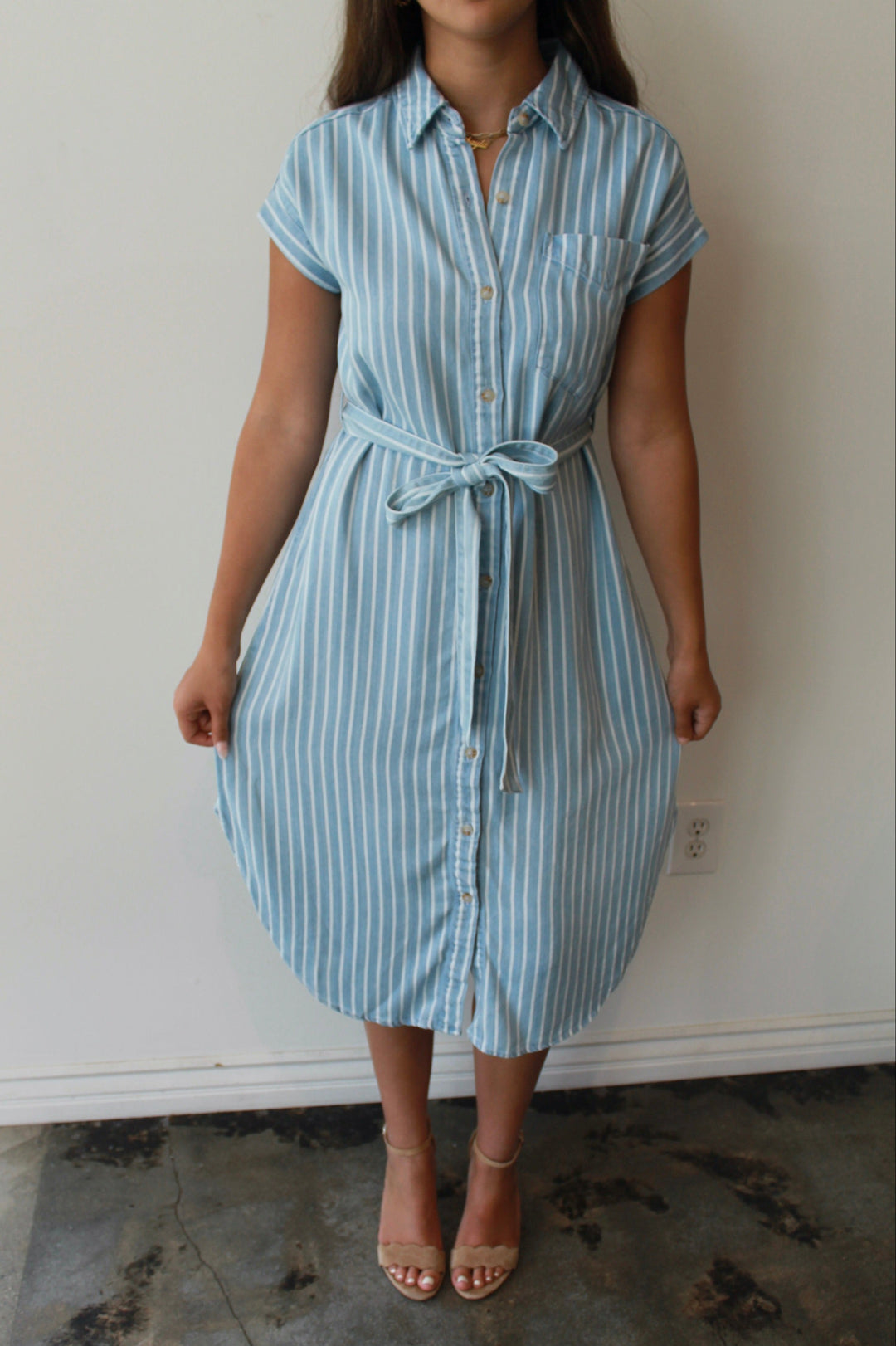 Person wearing a blue and white striped dress against a plain background