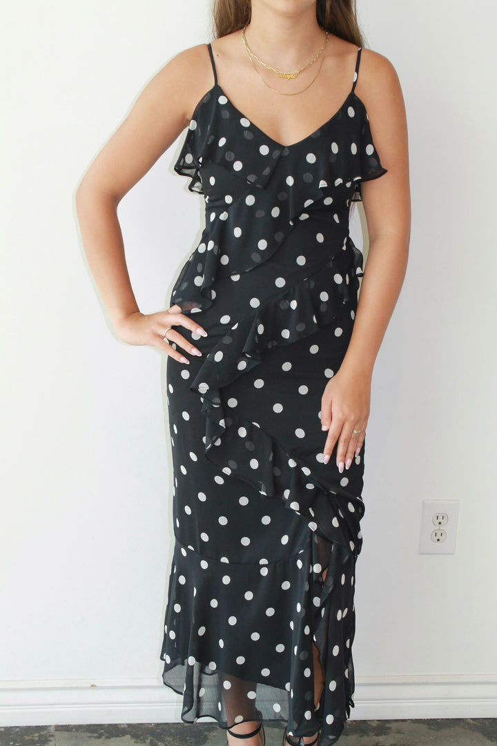 Woman wearing a black dress with white polka dots against a plain background