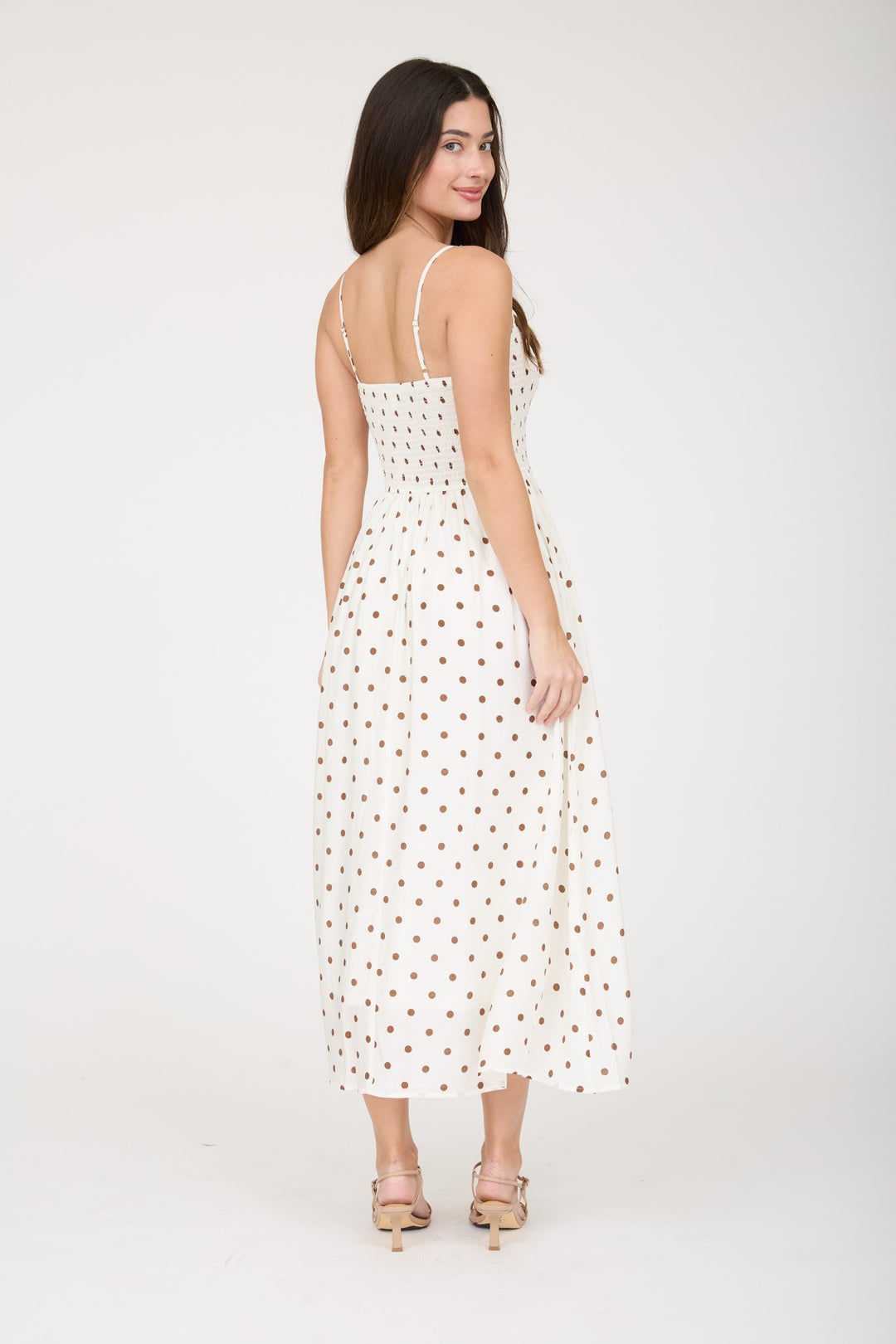 Woman wearing a white dress with brown polka dots on a white background