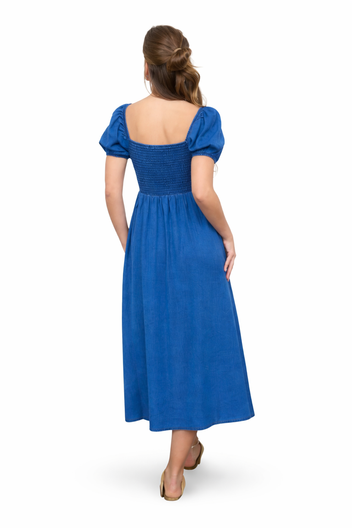 Back view of chambray blue smocked midi dress with puff sleeves and flowy skirt on white background