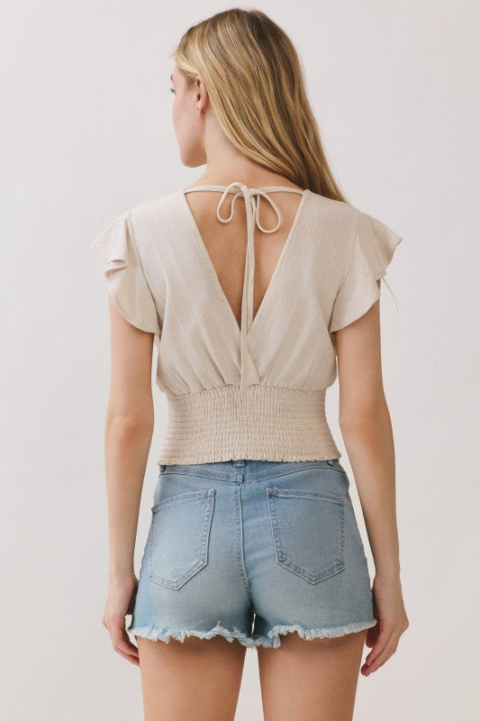 Back view of beige linen top with tie detail and smocked waist
